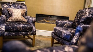 A living room with two patterned armchairs and a fireplace. - Arden House (Stratford-upon-Avon)