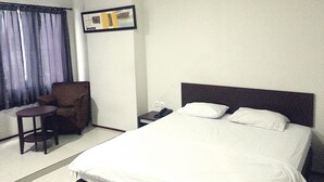 A hotel room with a large bed, a chair, a small table, and a nightstand. - Hotel Fiducia Otista 153 (Jakarta)