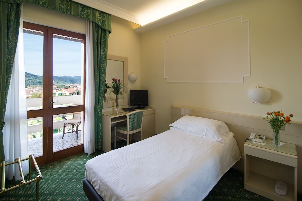 Een hotelkamer met een bed, bureau, stoel en uitzicht door een glazen deur.
