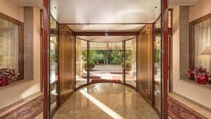 Um corredor com piso lustroso, portas de madeira e vista para um jardim com caminho.