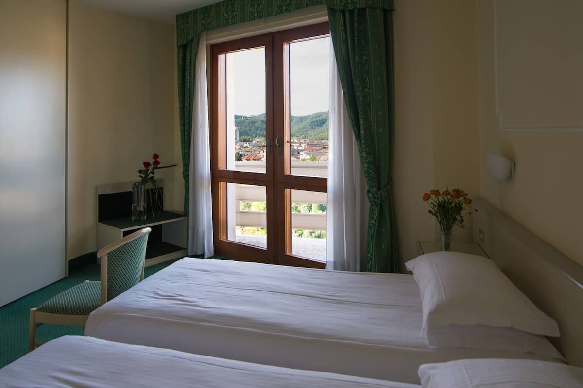 Een hotelkamer met een bed, een bureau en een raam met gordijnen.