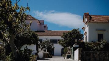 A quiet street with traditional buildings, a clear sky, and a stone wall.