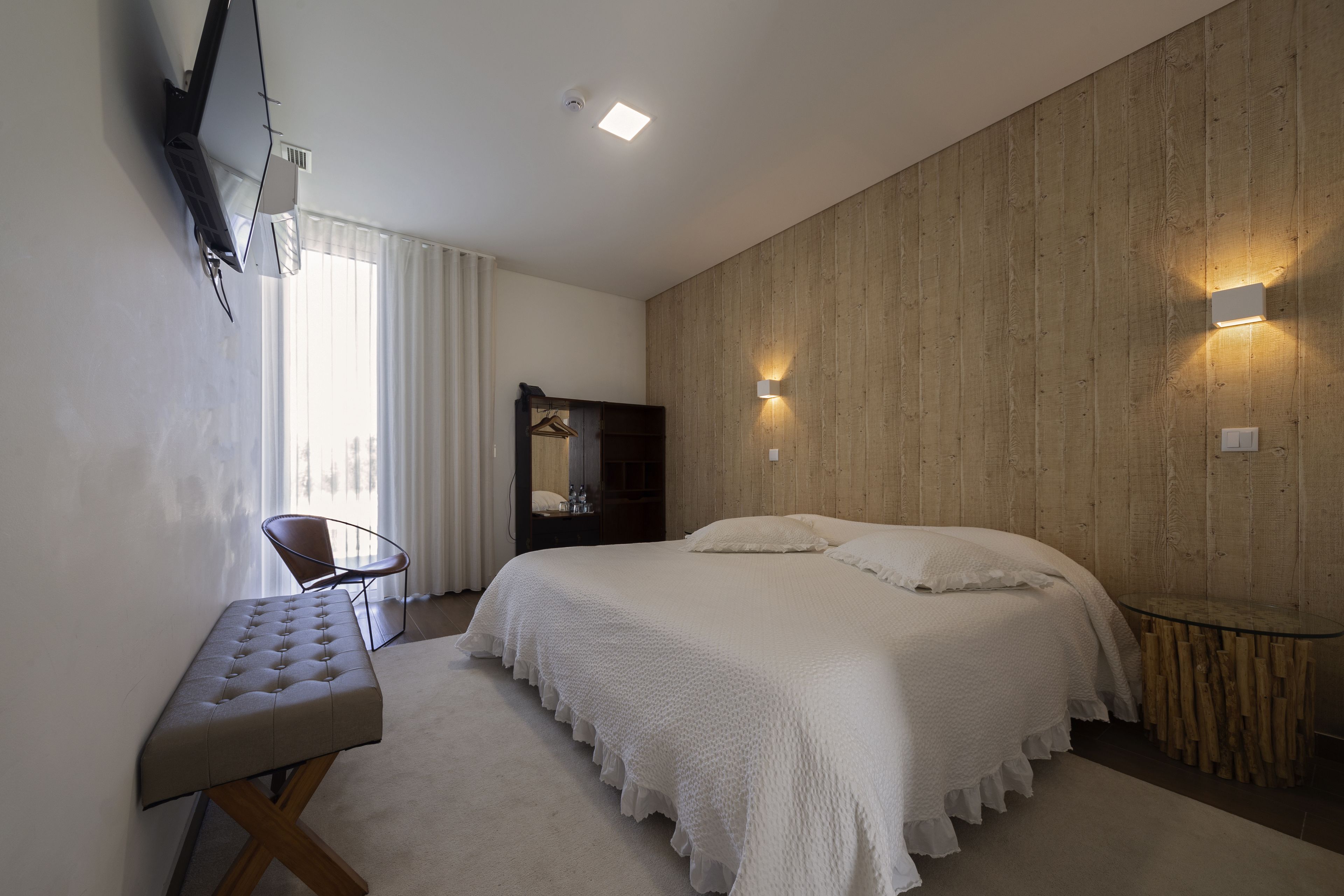 Une chambre à coucher avec un grand lit, une chaise, une petite table et un miroir.