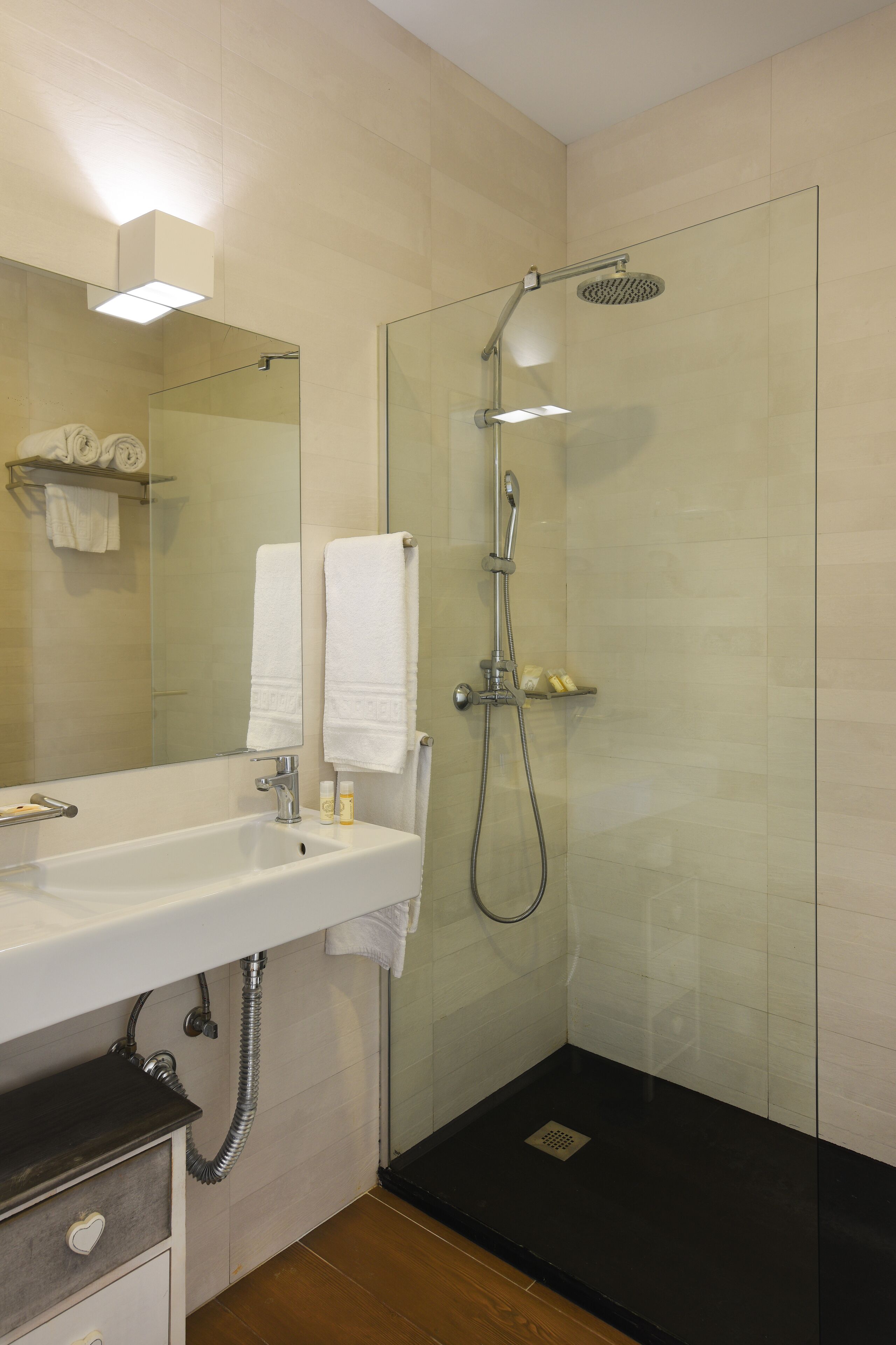 A modern bathroom with a glass-enclosed shower, a white sink, and a mirror.