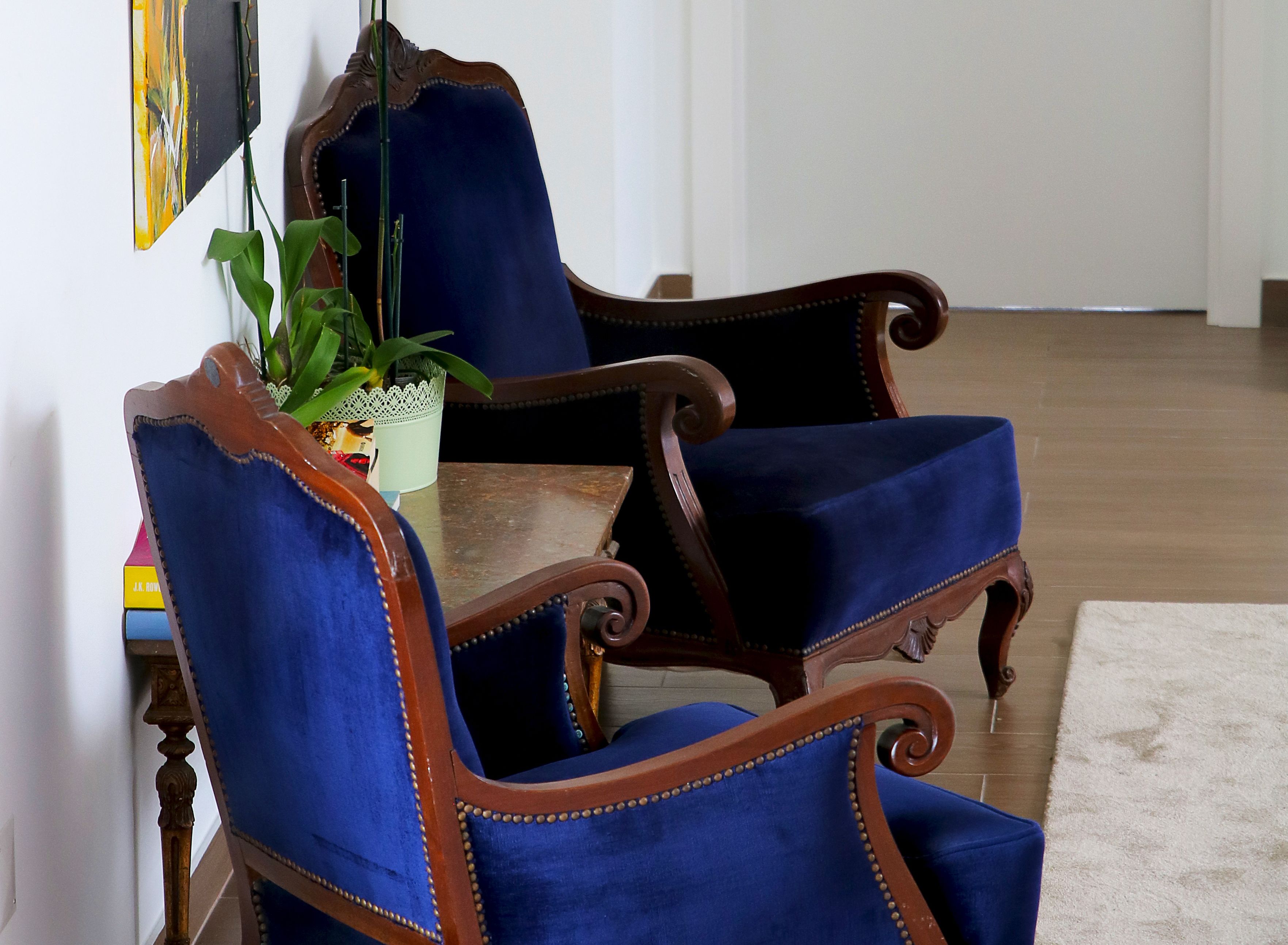 Una habitación con dos sillones tapizados en azul, con estructura de madera y una pequeña mesa.