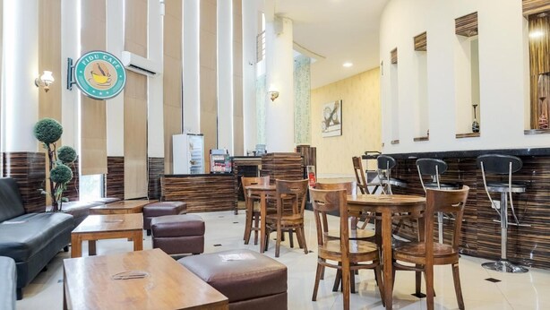 A modern lobby with wooden furniture, a reception desk, and a wall-mounted sign.