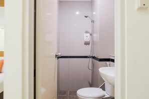 A small, modern bathroom with a toilet, sink, and shower. - Hotel Fiducia Serpong (South Tangerang)