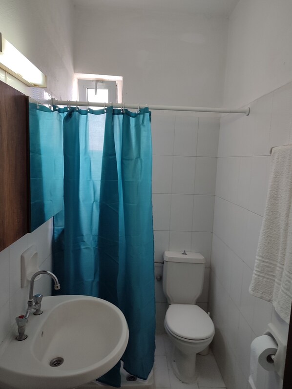 Un baño con lavamanos blanco, inodoro y cortina de ducha azul.