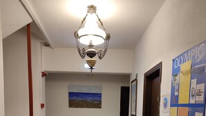 Käytävä, jossa on puinen penkki, punainen kaappi ja seinä, jossa on olympiateemainen ilmoitustaulu.