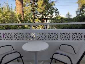 A balcony with two chairs and a small round table, surrounded by a white decorative fence. - Dolphin Apartments (Rhodes)