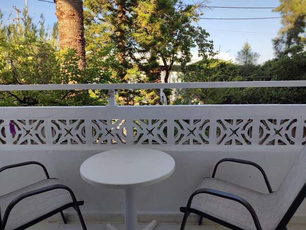 A balcony with two chairs and a small round table, surrounded by a white decorative fence. - Dolphin Apartments (Rhodes)