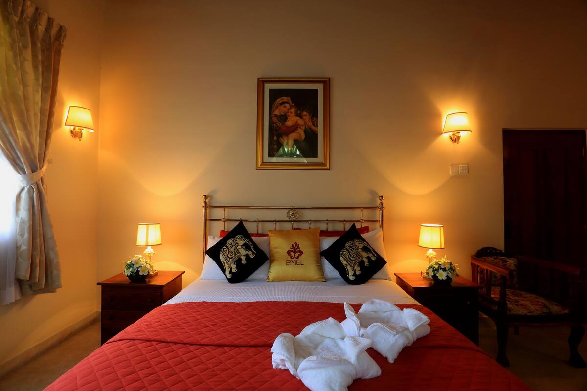 A hotel room with a bed, two nightstands, a chair, and a painting on the wall.