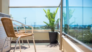 Un balcone con sedie in vimini e una pianta in vaso, con vista sulla città.