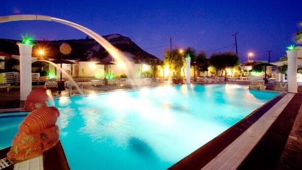 Una piscina con giochi d'acqua e illuminazione notturna.