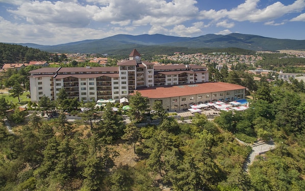 A large hotel with multiple floors, a prominent clock tower, and a courtyard with outdoor seating.