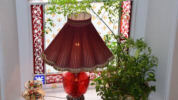Una lámpara roja sobre un soporte, una planta en maceta y un adorno en el alféizar de una ventana.