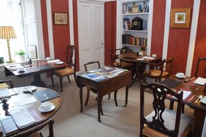 A dining area with a wooden table, chairs, and a bookshelf filled with books and decorative items. - The Townhouse (Perth)