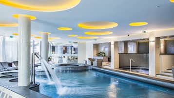 Een modern binnenzwembad met een waterglijbaan, ligbedden en een zithoek met uitzicht op het zwembad.