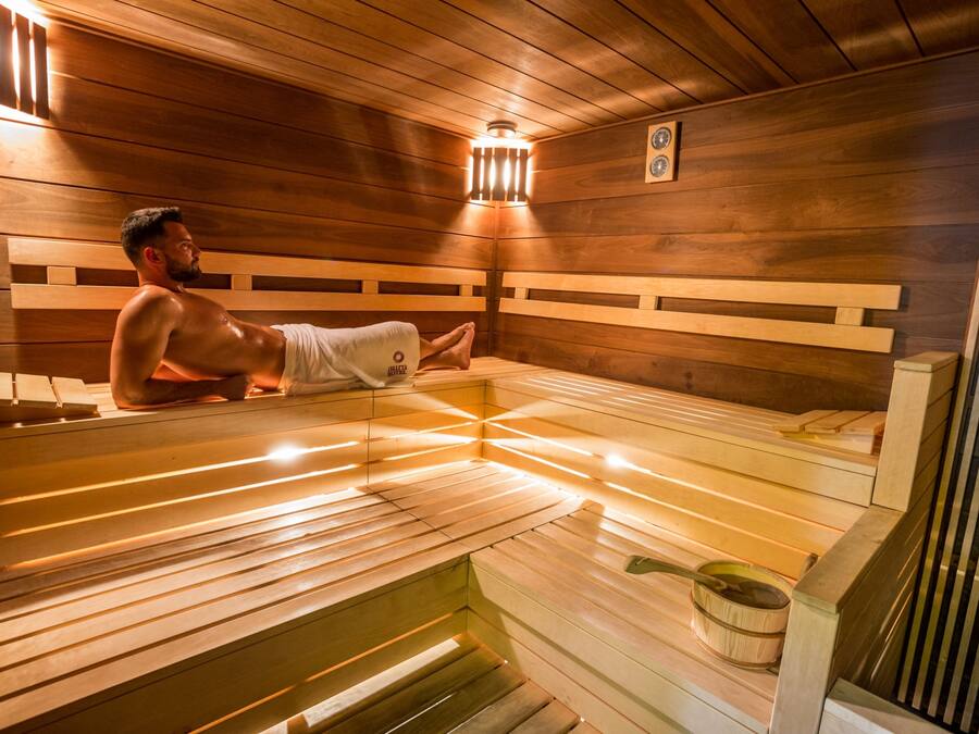 Eine Sauna mit Holzbänken und einem Ofen zum Aufheizen.