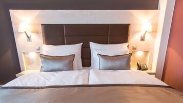 Ein Hotelzimmer mit einem großen Bett, zwei Nachttischlampen und einem Telefon auf dem Nachttisch.
