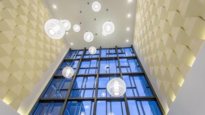 Un interior moderno con paredes de diseño geométrico, ventanas amplias y varios ventiladores de techo.