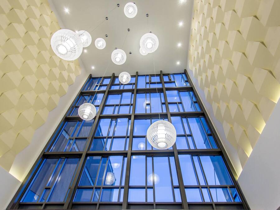 A modern interior with geometric patterned walls, large windows, and multiple ceiling fans.