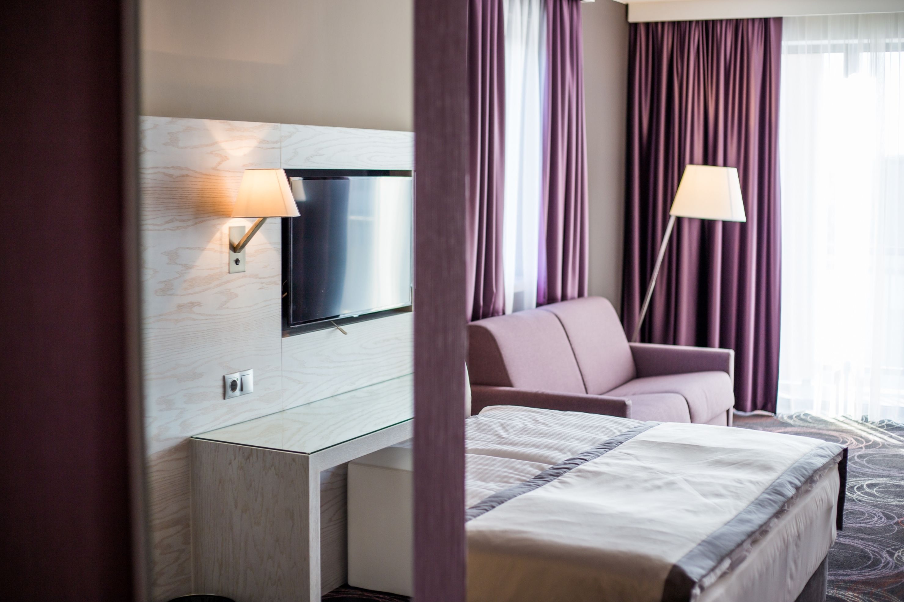 Une chambre d’hôtel avec un lit, un téléviseur fixé au mur, un bureau et une chaise.