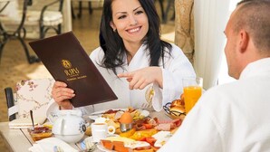 A breakfast setting with a variety of foods, a menu, and a cup of coffee. - St. Spas Hotel & Balneo Complex (Velingrad)