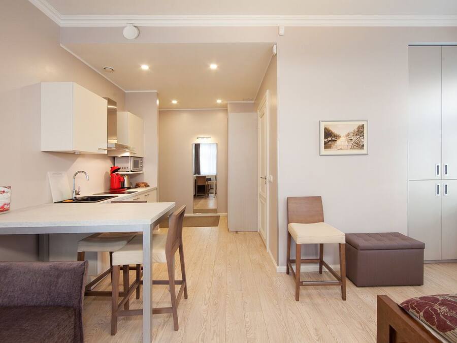 Um espaço de estar compacto com cozinha compacta, área de refeições e zona de estar com sofá e apoio para os pés.