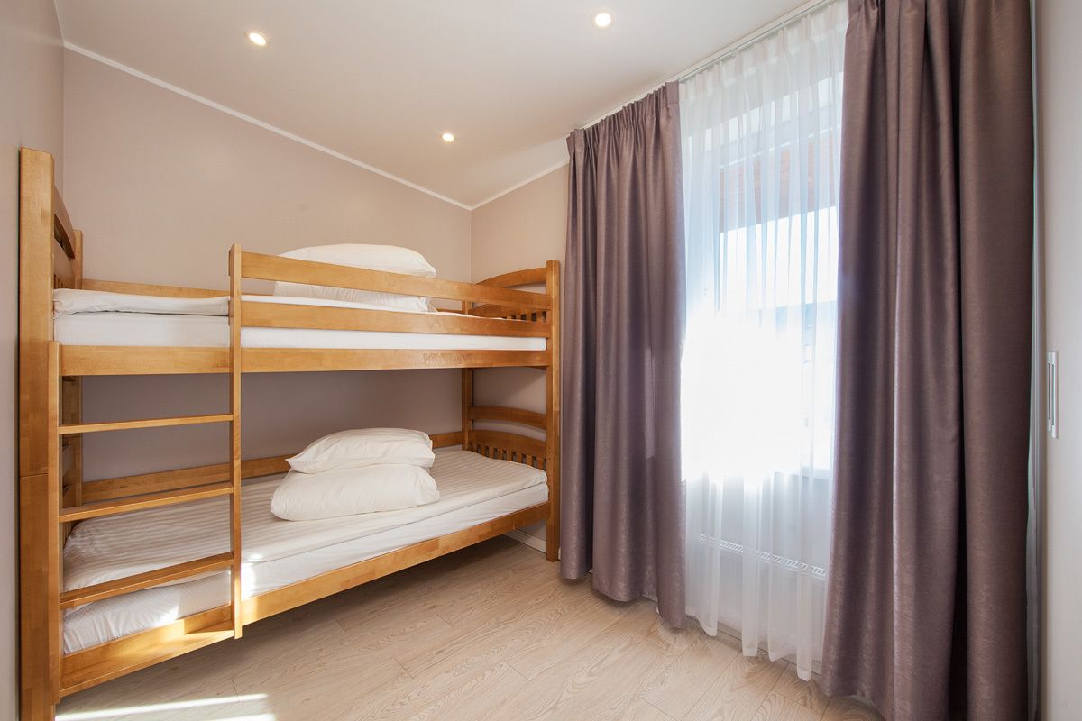 A bunk bed room with a window and curtains.