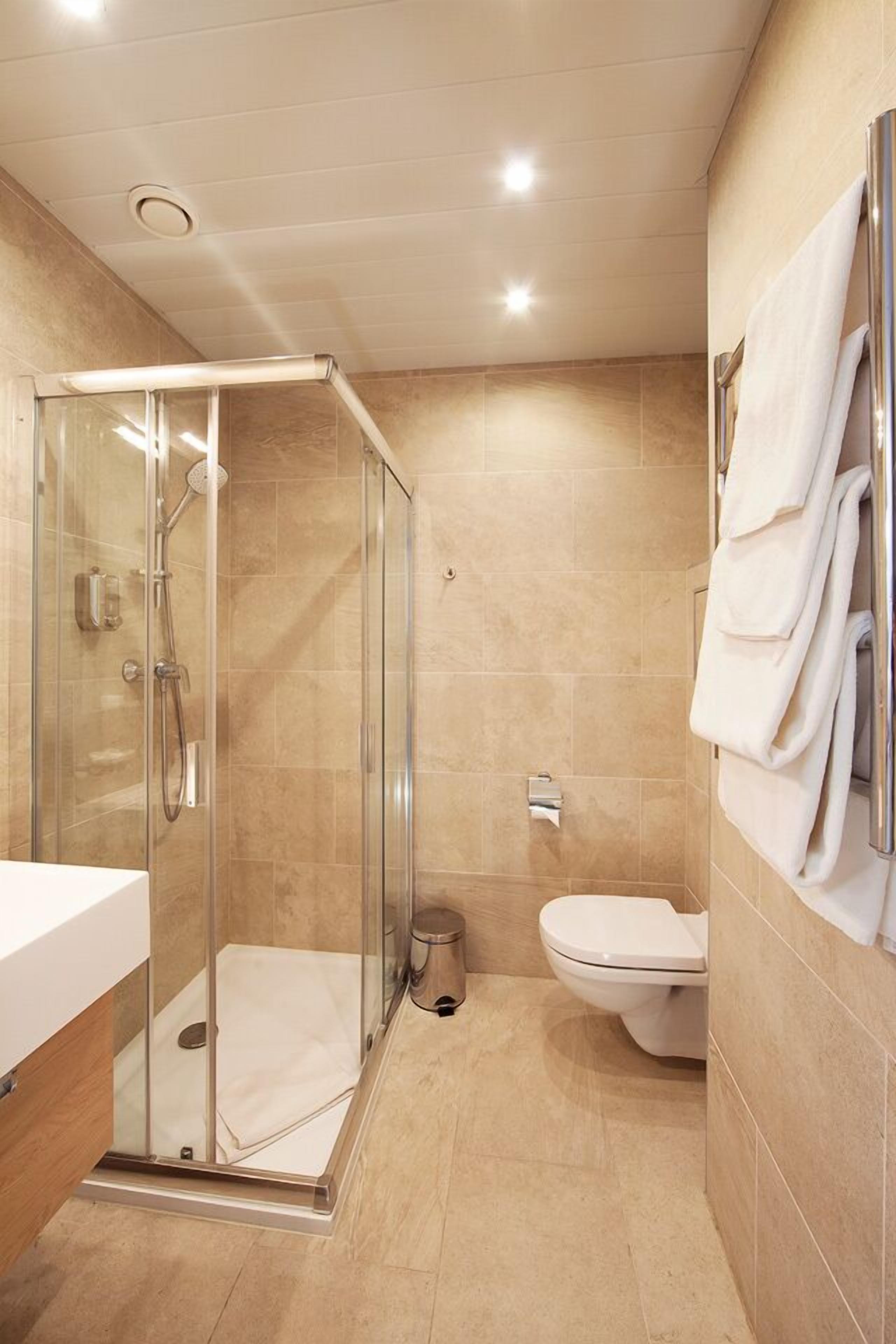 A modern bathroom with a glass-enclosed shower, a toilet, and a sink with a mirror.