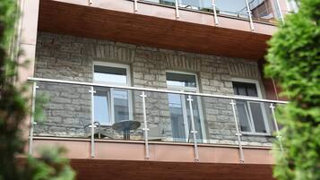 A multi-story building with stone facade, balconies with glass railings, and a wooden beam structure.