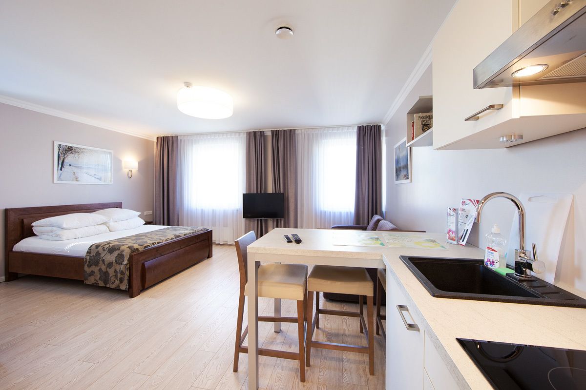 Une chambre d’hôtel avec un lit, un bureau doté d’un lavabo, une télévision et une fenêtre avec des rideaux.