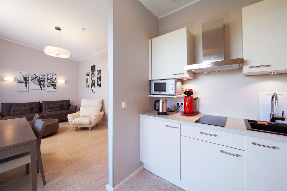 A modern kitchen with white cabinets, a microwave, and a red coffee maker.