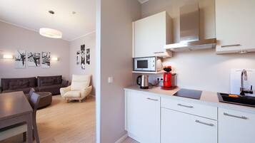 A modern kitchen with white cabinets, a microwave, and a red coffee maker.