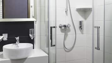 A modern bathroom with a white sink, a glass shower enclosure, and a mirror above the sink.