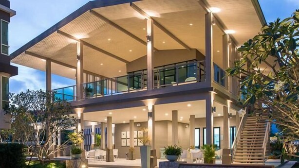 A modern multi-story building with a covered outdoor area, large windows, and a staircase leading to an upper level. - Baan Peang Ploen by Montri (Hua Hin)