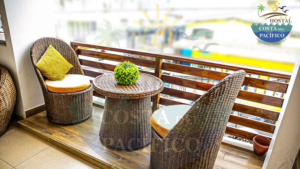 Un balcon agrémenté de meubles en osier, une petite table avec une plante et une vue sur la rue.