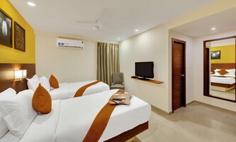 Habitación de hotel con dos camas, televisor, una silla y un escritorio con computadora.
