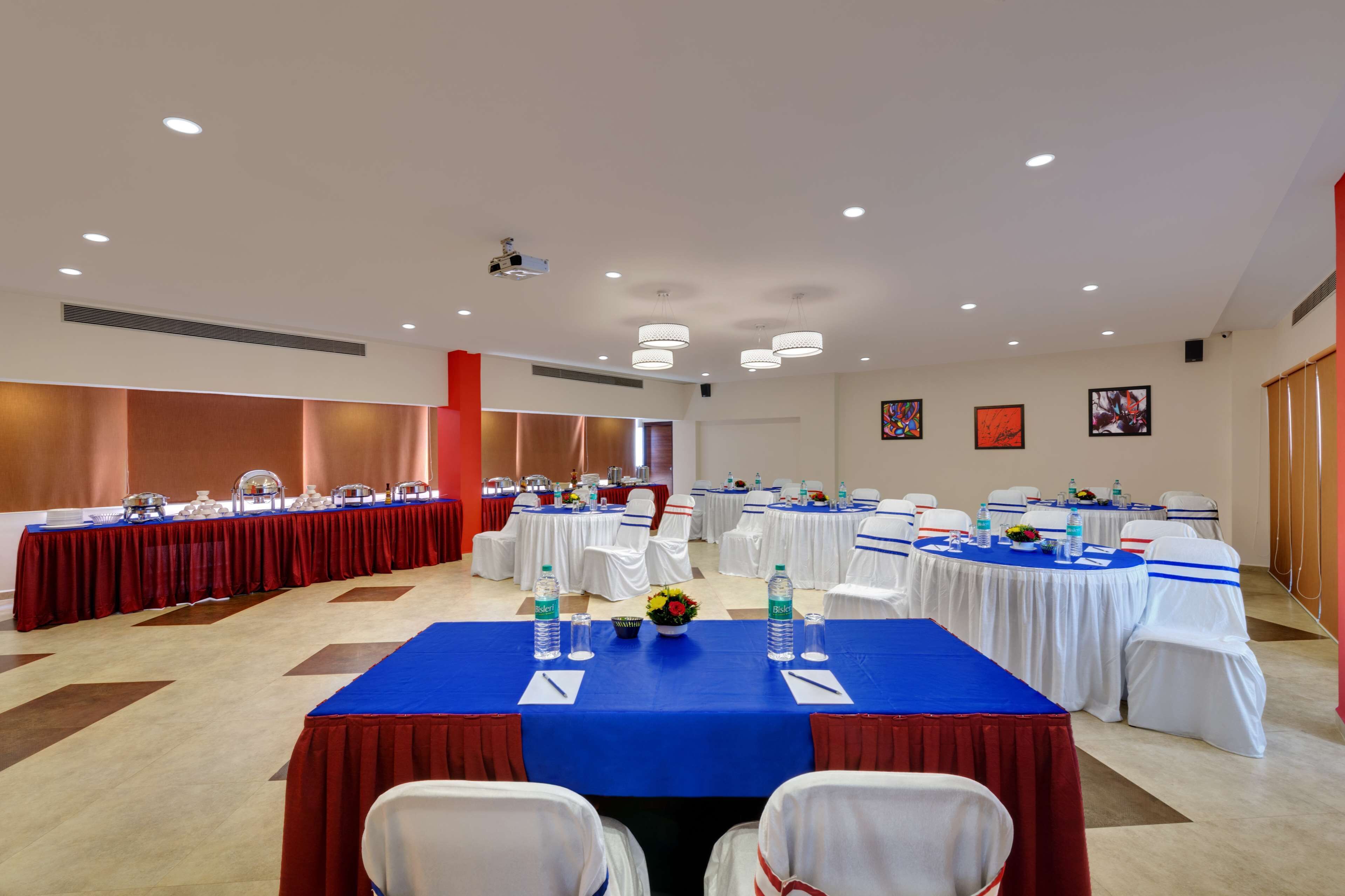 A conference room with multiple tables, white chairs, and blue tablecloths.