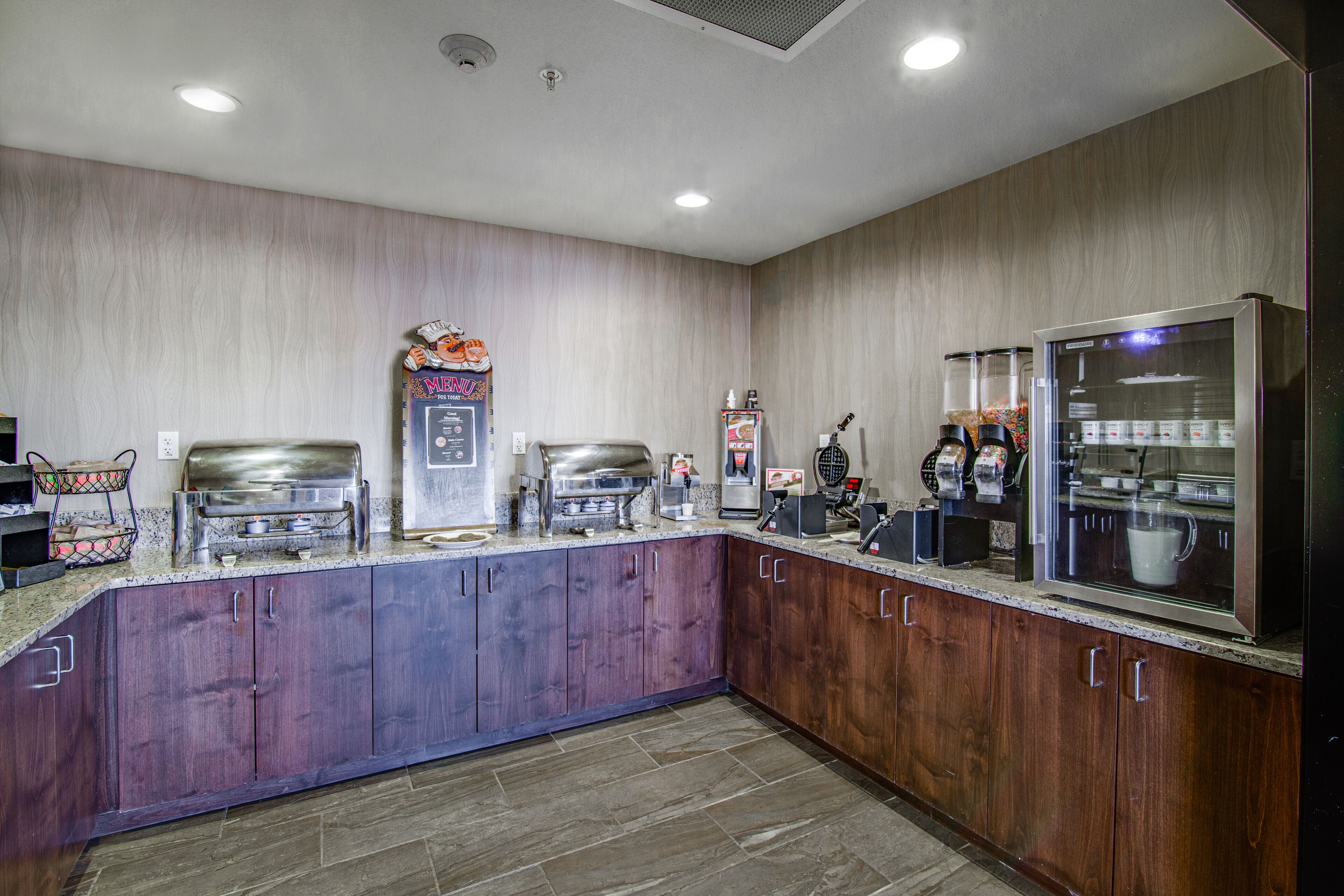 A commercial kitchen with stainless steel appliances, a menu board, and a coffee machine.