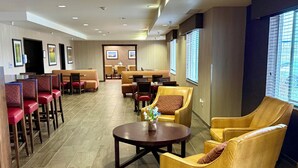 A hotel lobby with seating areas, a reception desk, and framed pictures on the walls. - Inn at Hunters Run (Watford City)