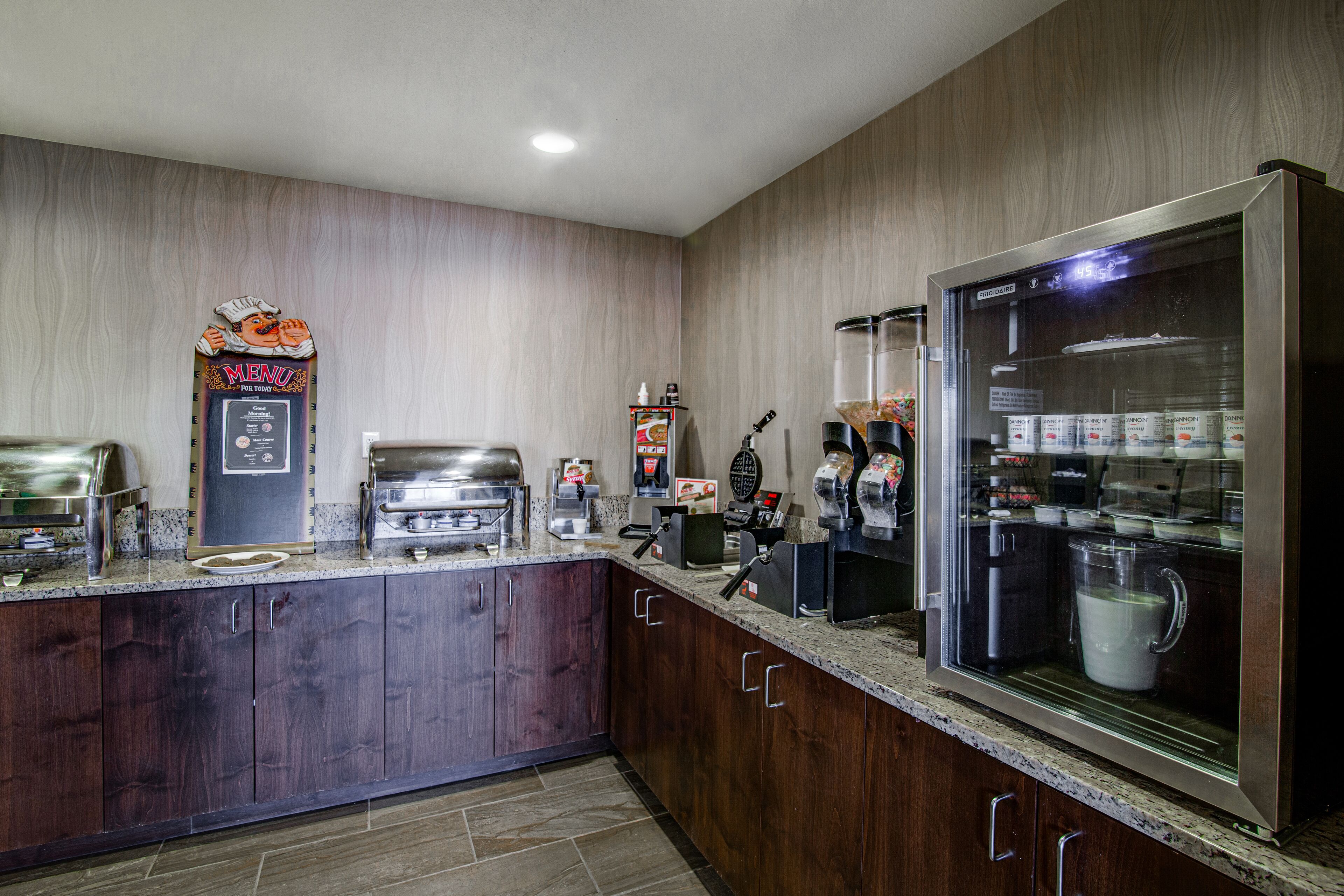 A kitchen with a refrigerator, coffee machine, and a microwave.