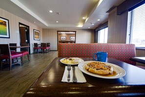 Un restaurant avec un plancher en bois, des banquettes rouges et une table dressée avec des gaufres et des œufs.