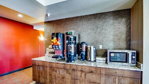A kitchen with a coffee machine, microwave, and coffee grinder. - Inn at Hunters Run (Watford City)