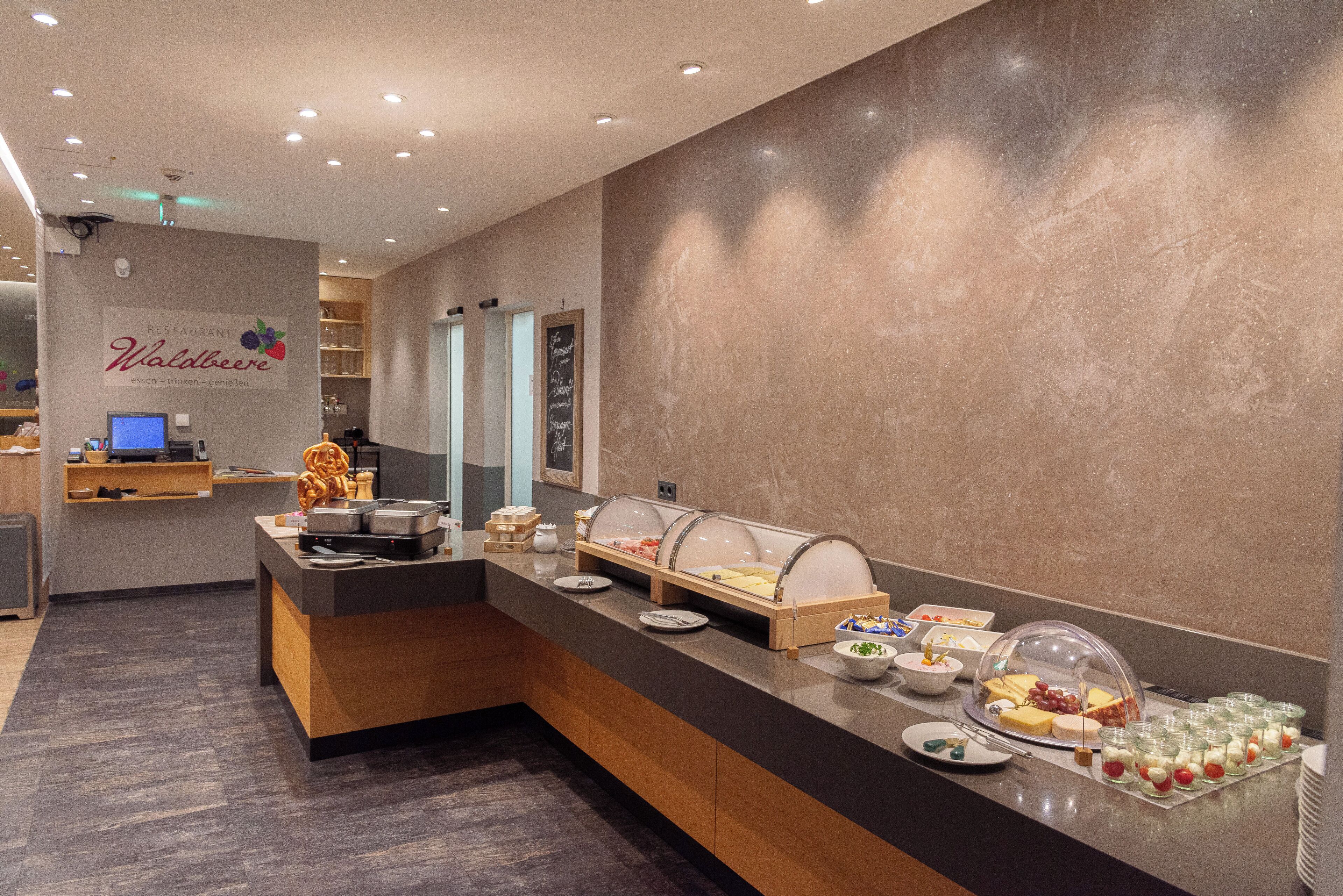 A buffet area with various food items and a sign for 'Restaurant Waldbeere' in the background.