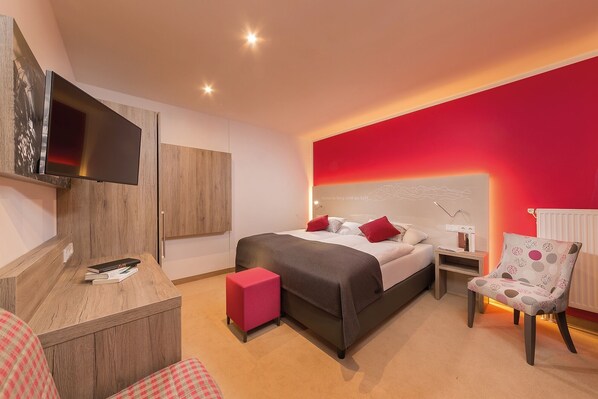 A modern hotel room with a bed, bedside tables, a TV, a desk, and a chair. - Allgäu ART Hotel Kempten (Kempten)
