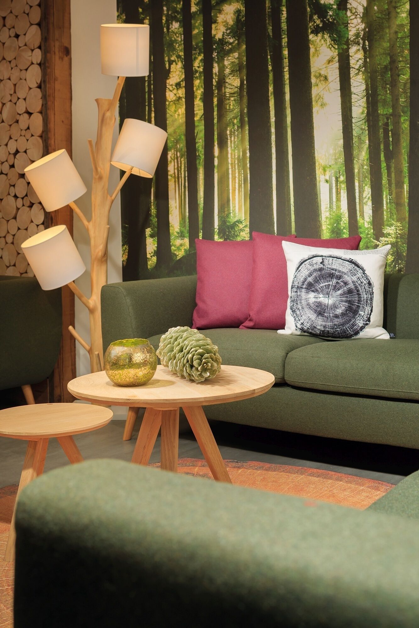 Un salon chaleureux avec un canapé vert, un lampadaire en bois et une table ronde en bois agrémentée d’objets décoratifs.
