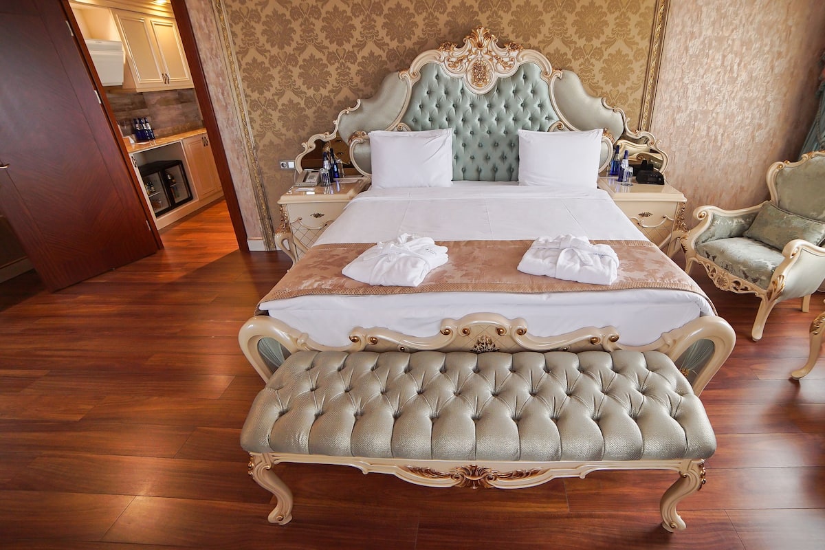 A luxurious bedroom with a large bed, ornate headboard, and a matching bench.
