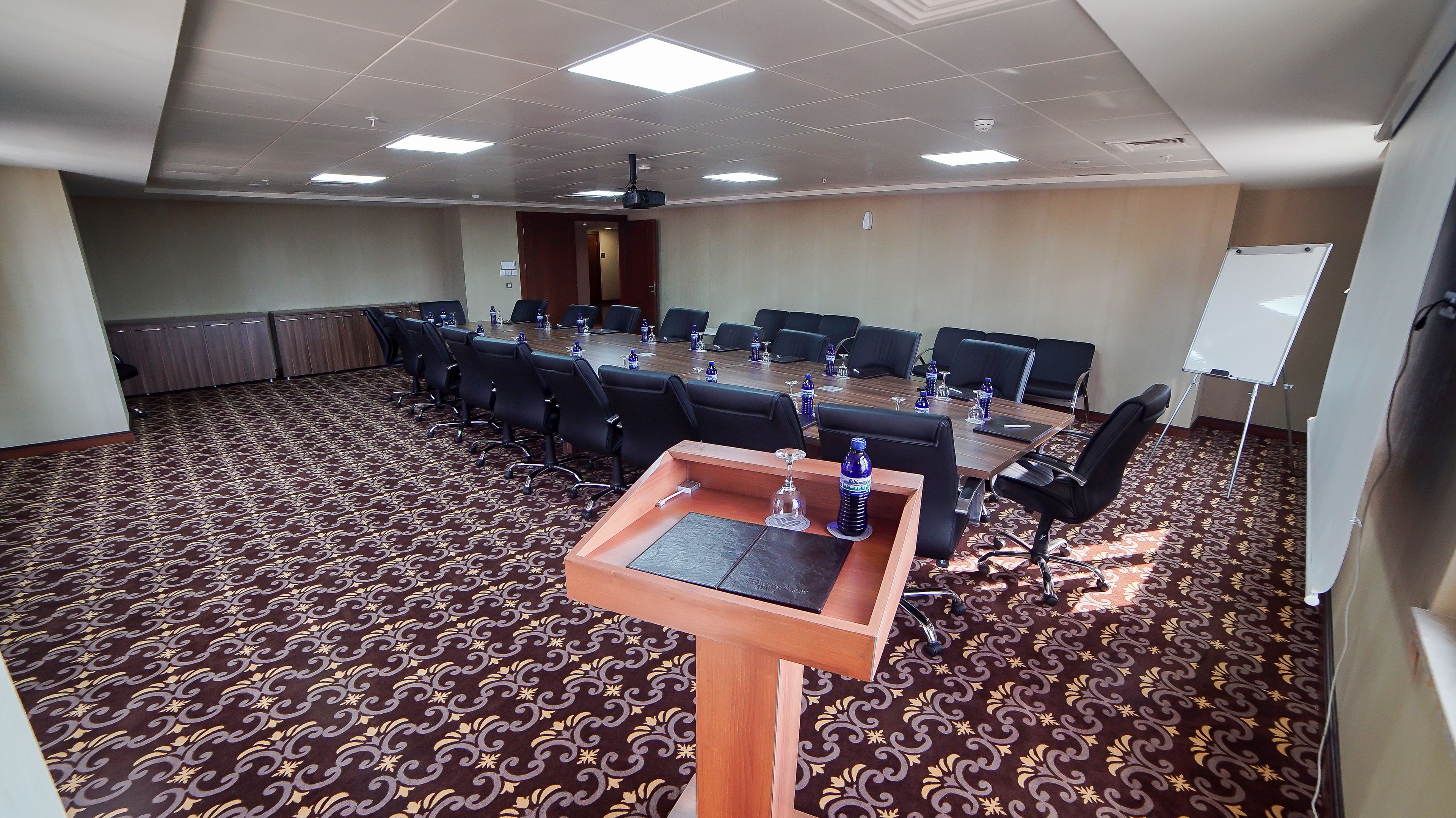 A conference room with a long table, multiple chairs, water bottles, and a whiteboard.